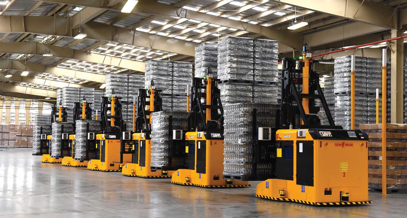 six yellow AGVs double loaded with pallets of glass bottles on display in a warehouse