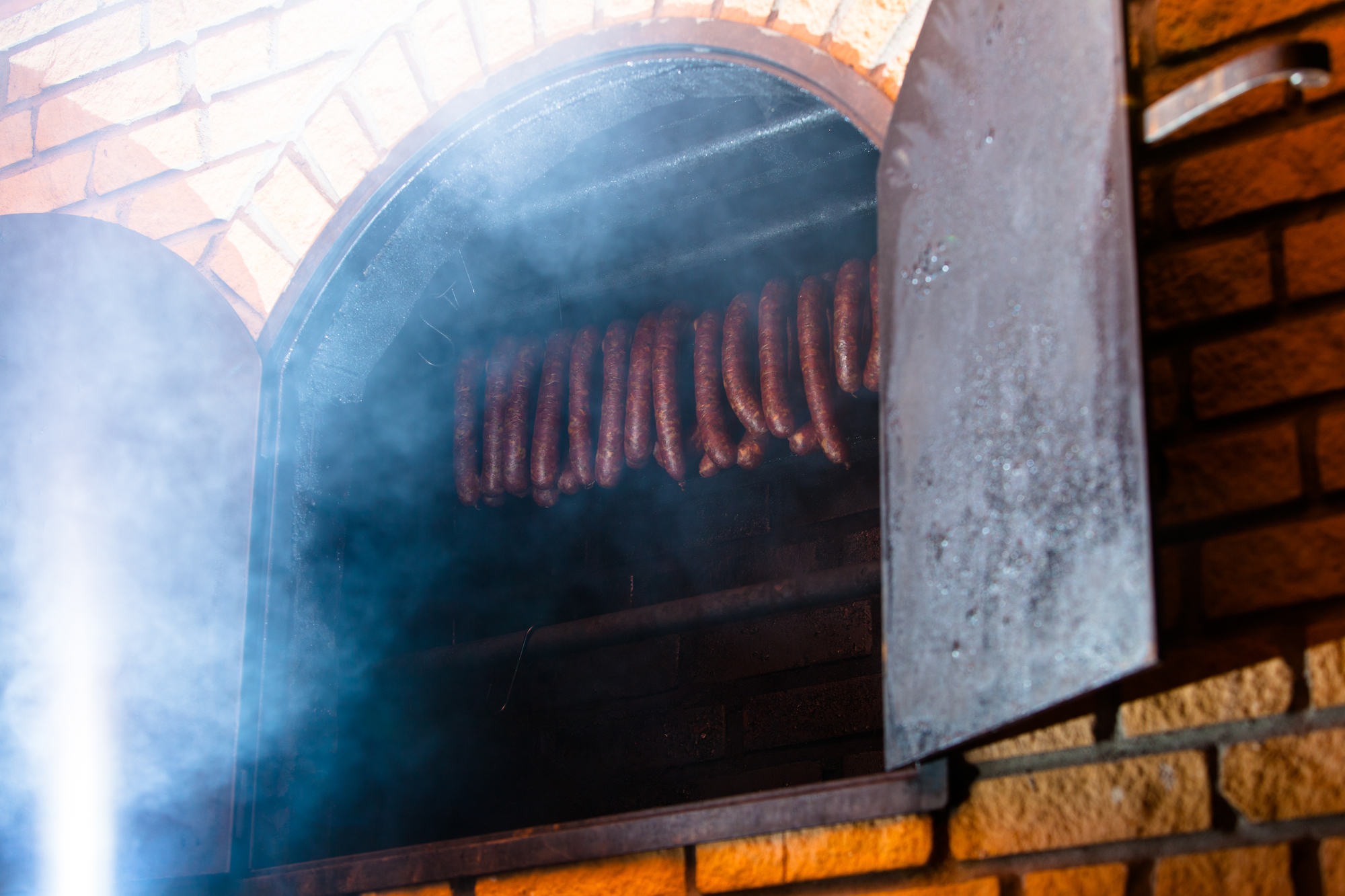 traditional brick smokehouse with smoked sausages being prepared